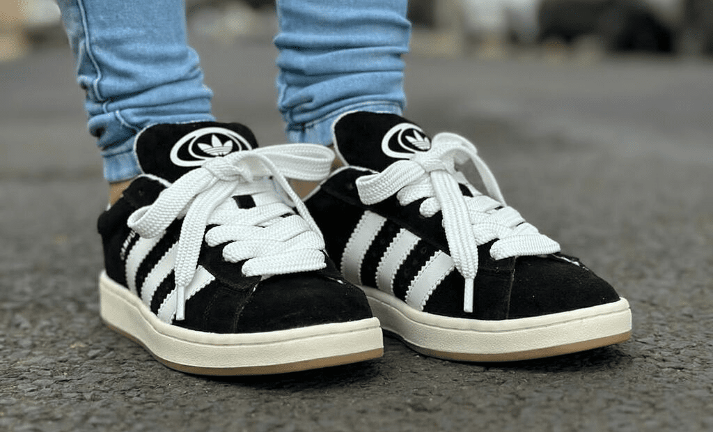 Descrições. Par de sapatilhas Adidas Campus 00s, de cor preta, com sola e cordões brancos.