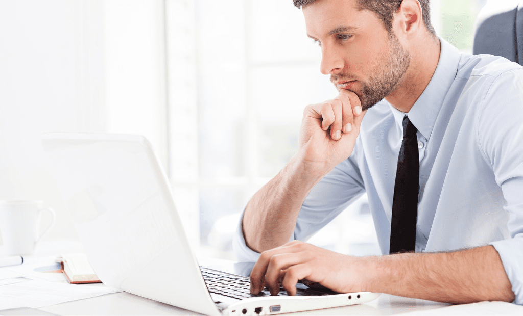 Homem pensativo a trabalhar num computador, representando a reflexão sobre a implementação de soluções de acessibilidade digital.