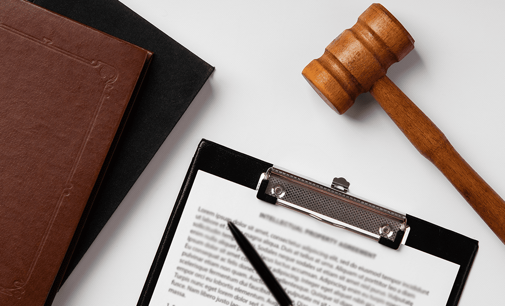 Leitor de ecrã. Martelo de juiz ao lado de um bloco de notas com documento e caneta, simbolizando legislação e políticas relacionadas com acessibilidade digital e direitos das pessoas com deficiência.